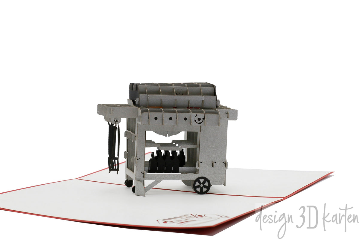 Aufgeklappte Pop-up-Karte mit einem Gasgrill aus Papier, seitlich fotografiert.