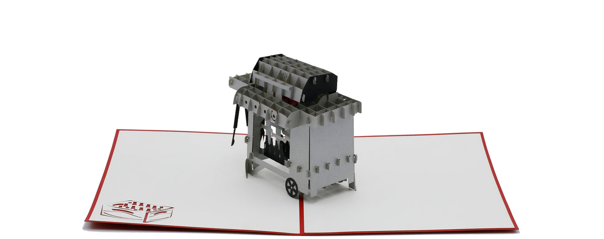 Aufgeklappte Pop-up-Karte mit Grill, von schräg oben fotografiert.
