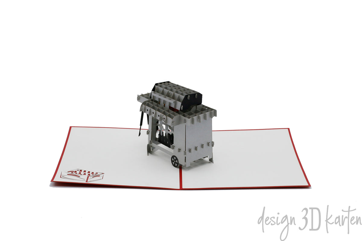 Aufgeklappte Pop-up-Karte mit Grill, von schräg oben fotografiert.