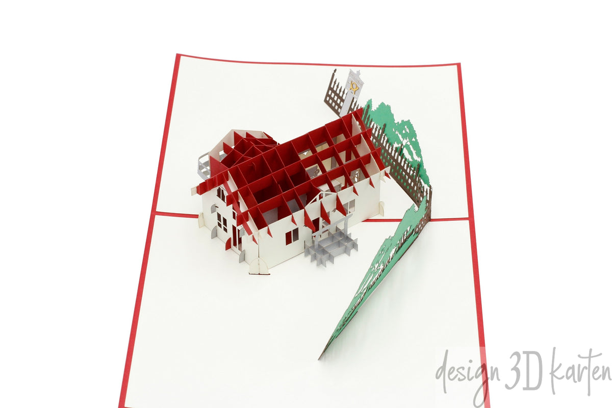 Nahaufnahme der aufgeklappten Pop-up-Karte mit einem Wohnhaus aus Papier.