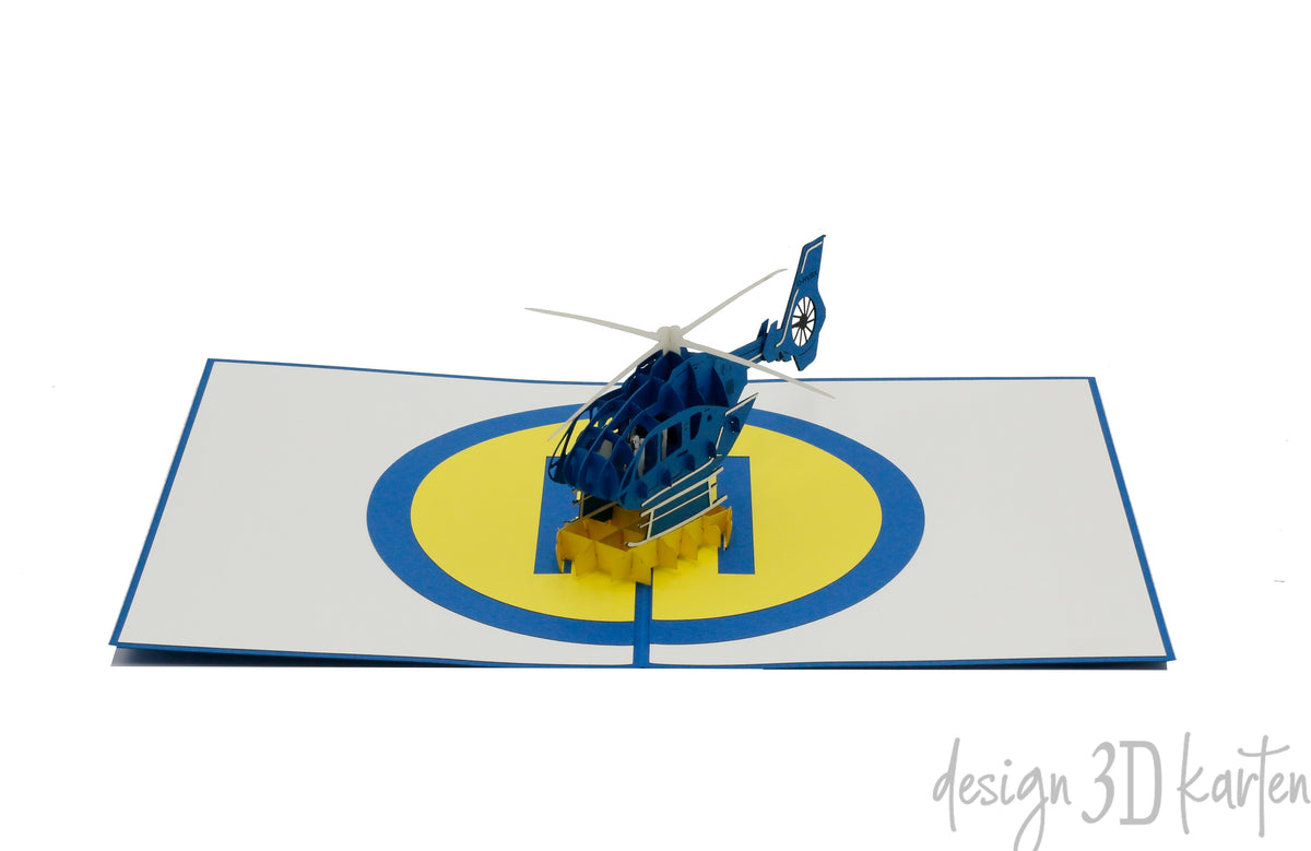 Aufgeklappte Pop-up-Karte mit Hubschrauber und Landeplatz, frontal fotografiert.