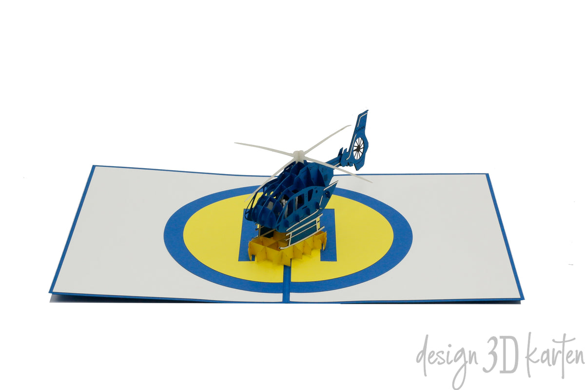 Aufgeklappte Pop-up-Karte mit Hubschrauber und Landeplatz, frontal fotografiert.