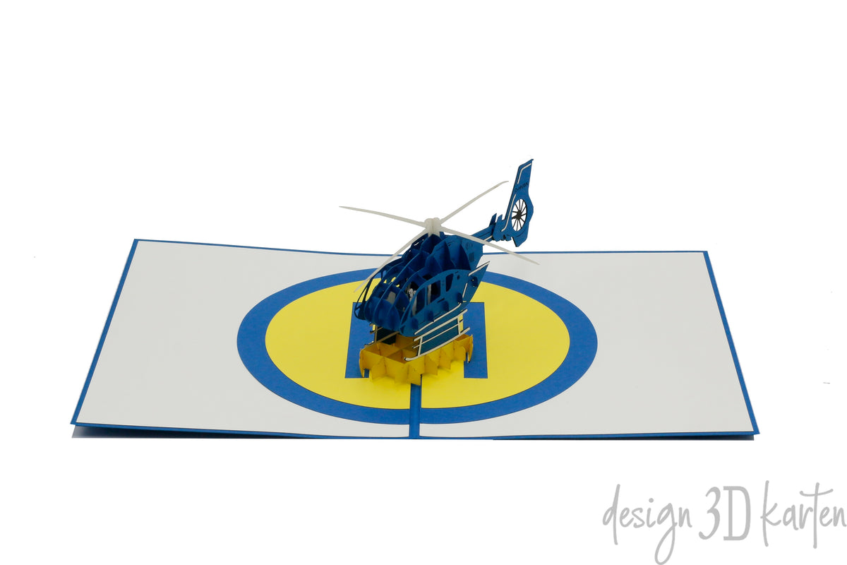 Aufgeklappte Pop-up-Karte mit Hubschrauber und Landeplatz, frontal fotografiert.