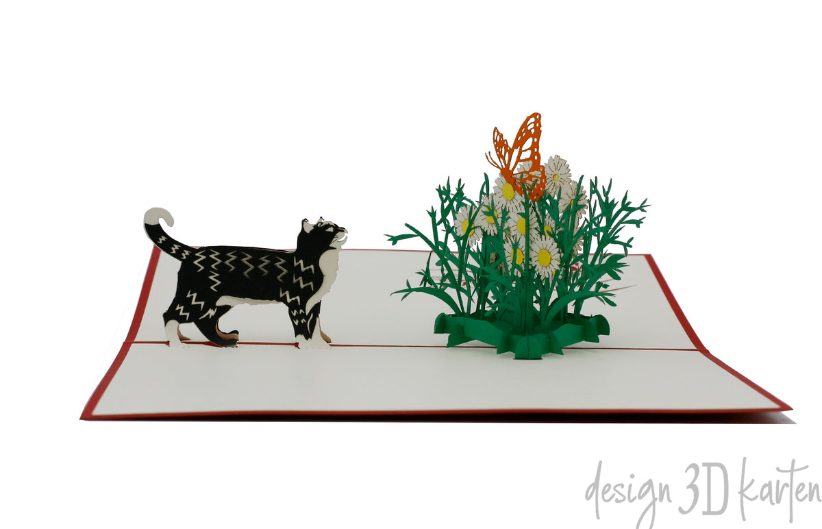 Aufgeklappte Pop-up-Karte mit Katze und Schmetterling aus Papier, frontal fotografiert.