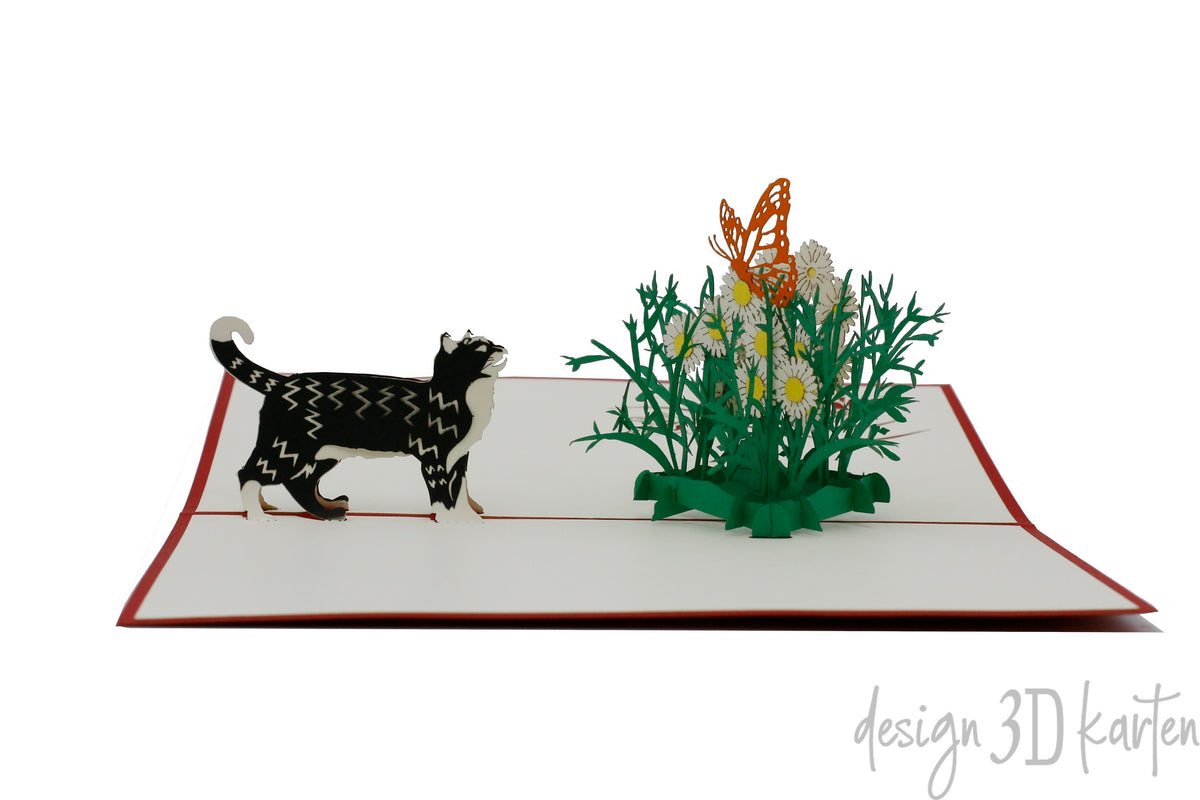 Aufgeklappte Pop-up-Karte mit Katze und Schmetterling aus Papier, frontal fotografiert.