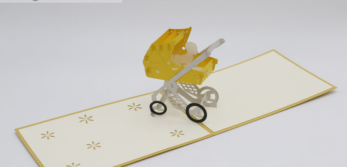 Aufgeklappte Pop-up-Karte mit gelbem Kinderwagen, schräg von oben fotografiert.