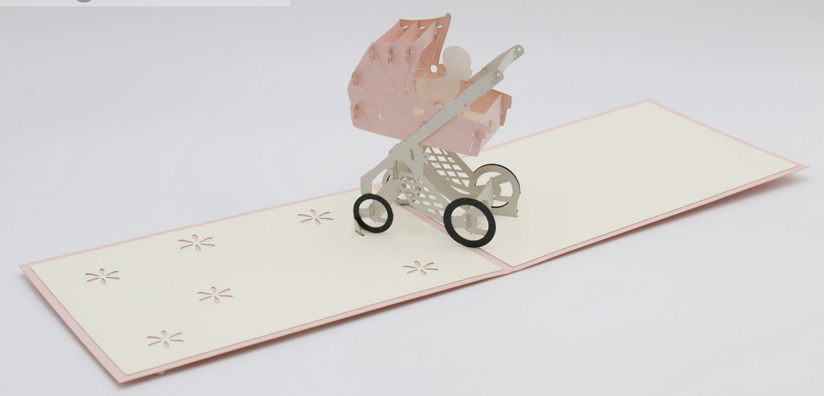 Aufgeklappte Pop-up-Karte mit rosa Kinderwagen, schräg von der Seite fotografiert.