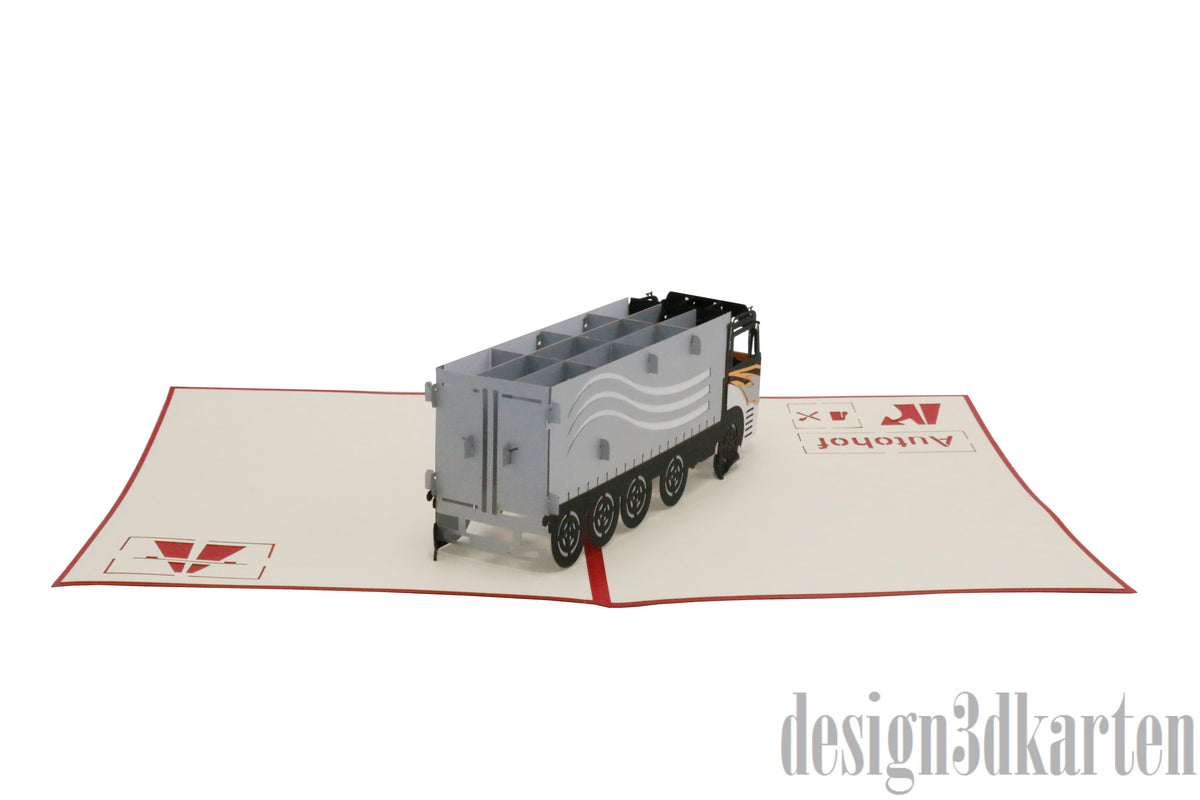 Aufgeklappte Pop-up-Karte mit LKW aus Papier, von schräg hinten fotografiert.