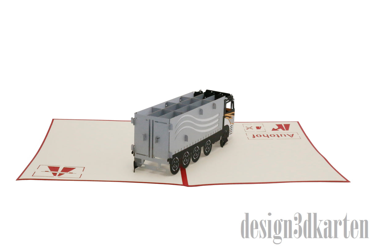 Aufgeklappte Pop-up-Karte mit LKW aus Papier, von schräg hinten fotografiert.