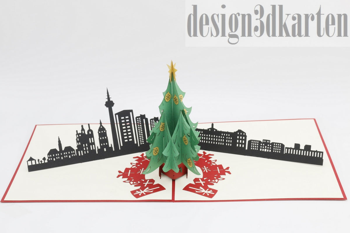 Aufgeklappte Pop-up-Karte mit grünem Weihnachtsbaum vor der schwarzen Skyline von Mannheim.