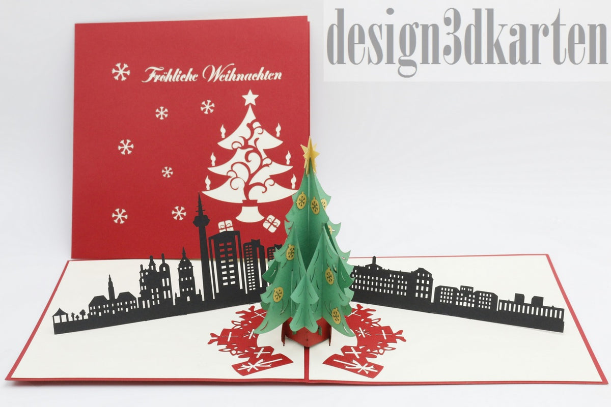 Aufgeklappte Pop-up-Karte mit Weihnachtsbaum und Mannheimer Skyline, daneben die rote Kartenvorderseite mit Weihnachtsbaum-Scherenschnitt.