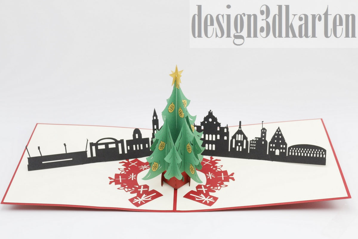 Aufgeklappte Pop-up-Karte mit grünem Weihnachtsbaum vor der schwarzen Skyline von Nürnberg.