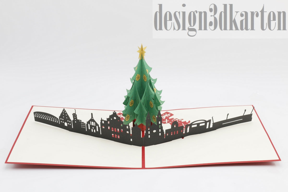 Aufgeklappte Pop-up-Karte mit Weihnachtsbaum vor der Skyline von Nürnberg, schräg von der Seite fotografiert.