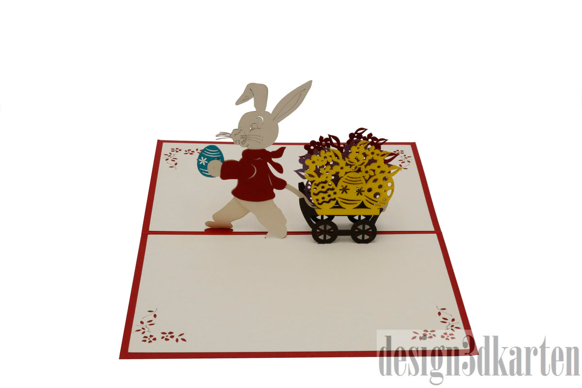 Aufgeklappte Pop-up-Karte mit Osterhase und Blumenwagen, schräg von oben fotografiert.