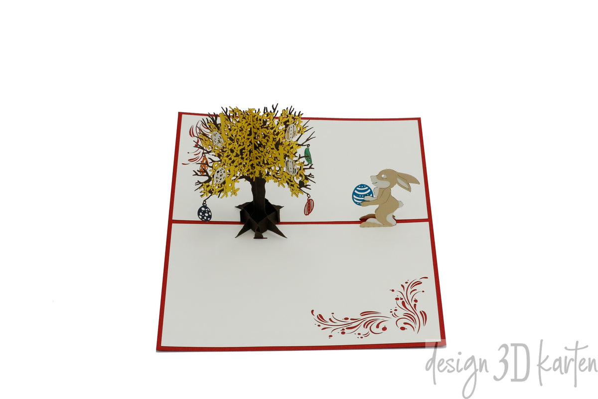 Aufgeklappte Pop-up-Karte mit Osterhase und Goldregenbaum, schräg von oben fotografiert.