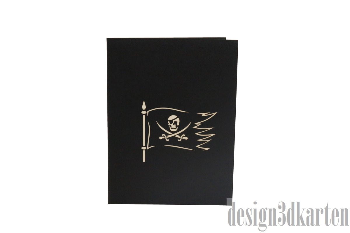 Schwarze Kartenvorderseite mit Piratenflagge, Säbel und Totenkopf als Scherenschnitt.
