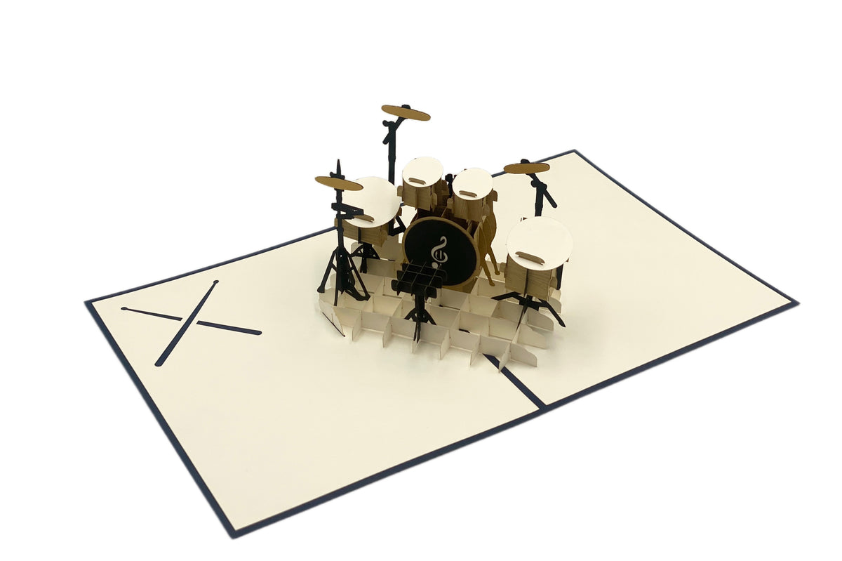 Aufgeklappte Pop-up-Karte mit einem Schlagzeug aus Papier, schräg von der Seite fotografiert.
