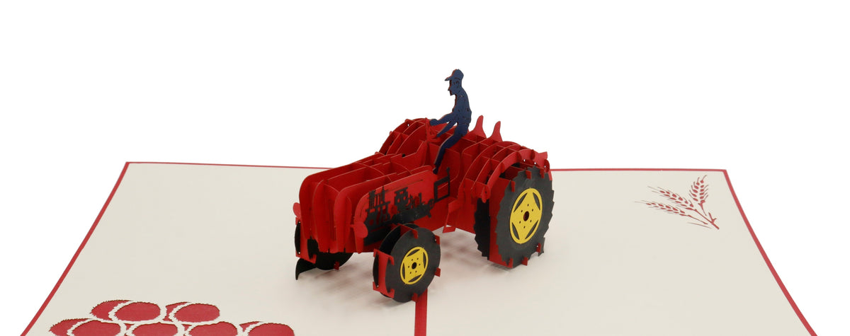 Aufgeklappte Pop-up-Karte mit rotem Rand und einem roten Oldtimer-Traktor mit Fahrer, auf der Kartenfläche rote Äpfel.