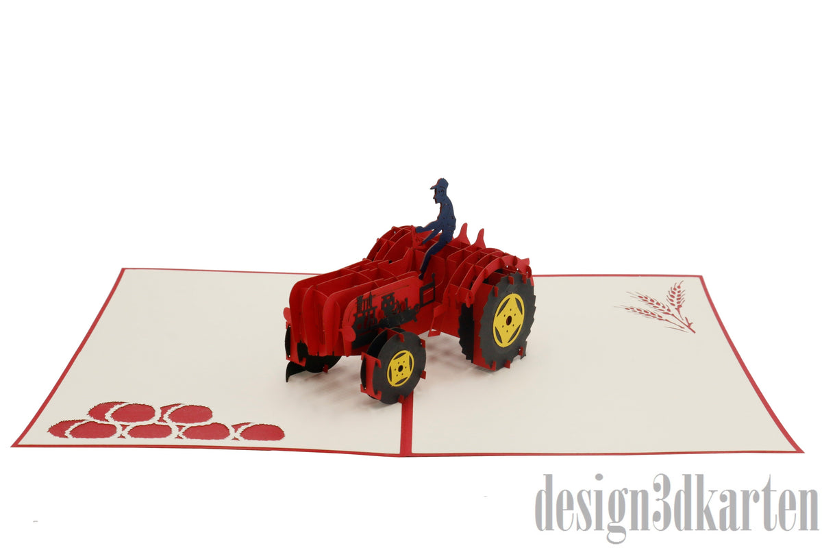 Aufgeklappte Pop-up-Karte mit rotem Rand und einem roten Oldtimer-Traktor mit Fahrer, auf der Kartenfläche rote Äpfel.