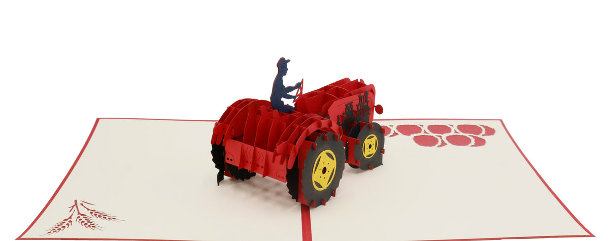 Aufgeklappte Pop-up-Karte mit rotem Oldtimer-Traktor aus Papier, von der anderen Seite fotografiert.