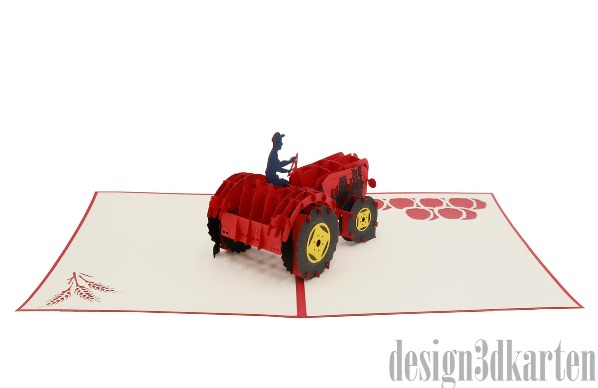 Aufgeklappte Pop-up-Karte mit rotem Oldtimer-Traktor aus Papier, von der anderen Seite fotografiert.