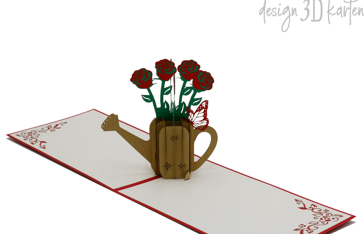 Aufgeklappte Pop-up-Karte mit Rosen in der Gießkanne, schräg von der Seite fotografiert.