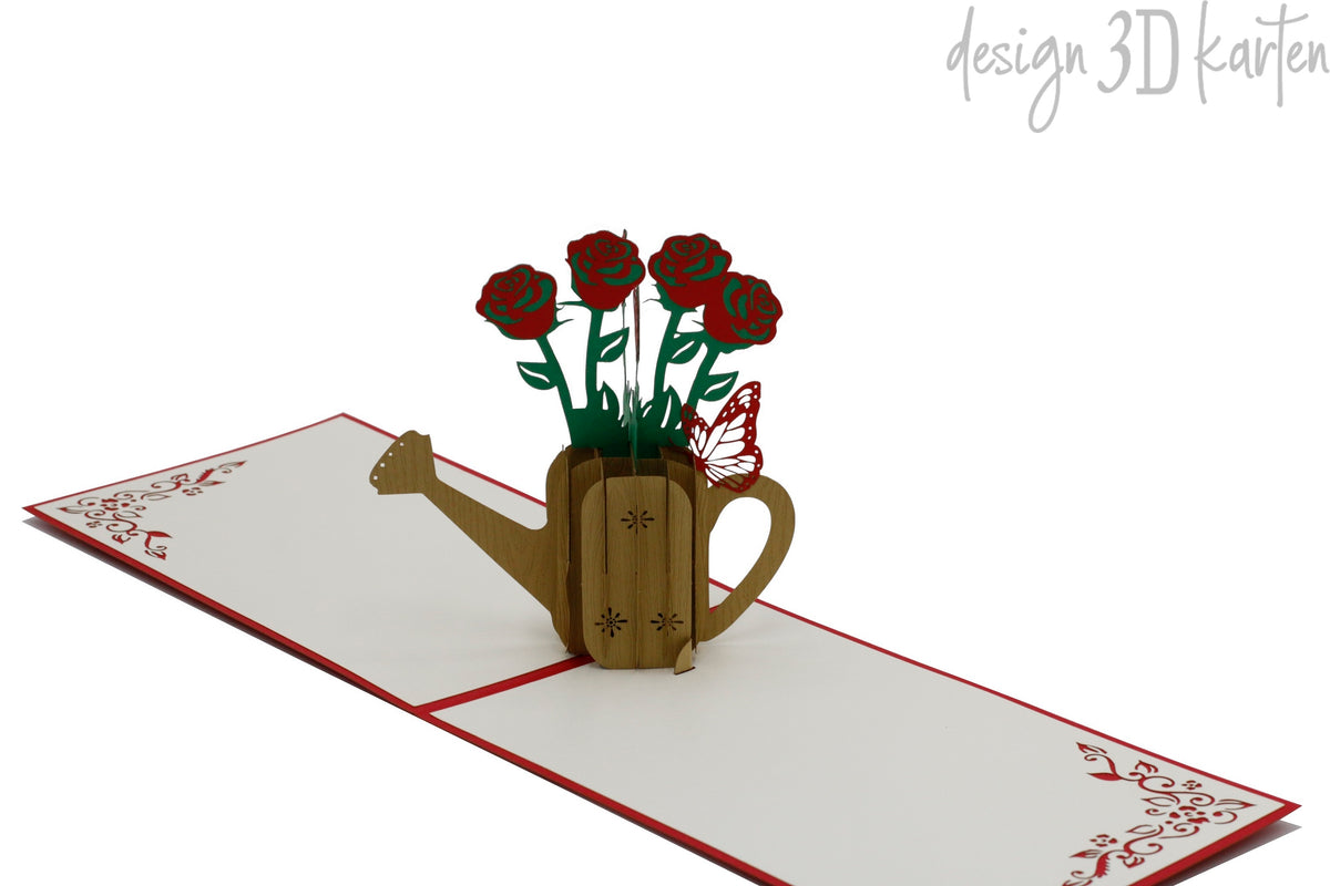 Aufgeklappte Pop-up-Karte mit Rosen in der Gießkanne, schräg von der Seite fotografiert.