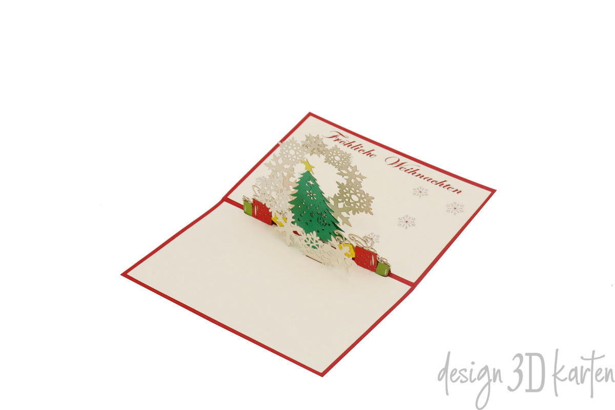 Aufgeklappte Pop-up-Karte mit Weihnachtsbaum, Geschenken und Schneeflocken, schräg von der Seite fotografiert.