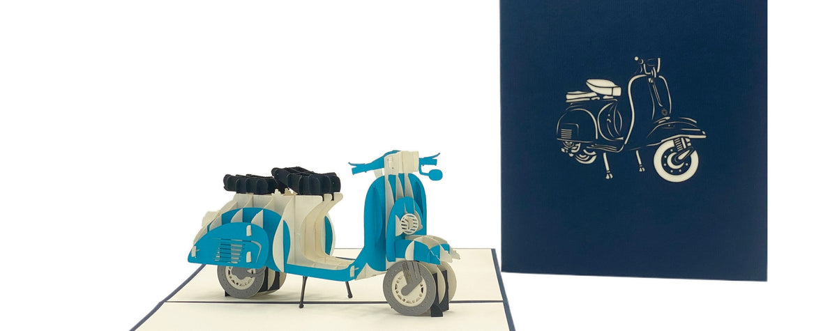 Aufgeklappte Pop-up-Karte mit blauer Vespa, daneben die dunkelblaue Kartenvorderseite mit Vespa-Scherenschnitt.