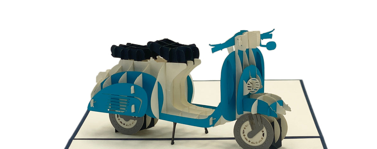 Nahaufnahme der aufgeklappten Pop-up-Karte mit einer blauen Vespa mit Gepäckträger.