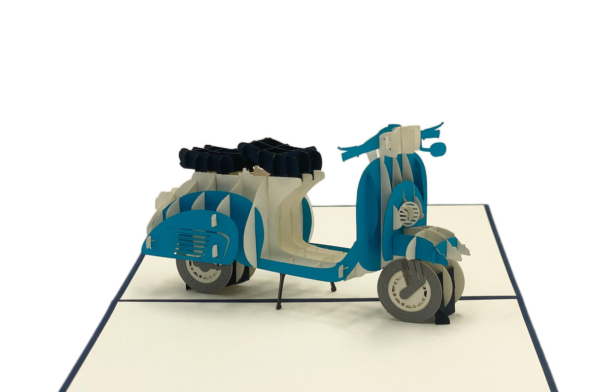 Nahaufnahme der aufgeklappten Pop-up-Karte mit einer blauen Vespa mit Gepäckträger.