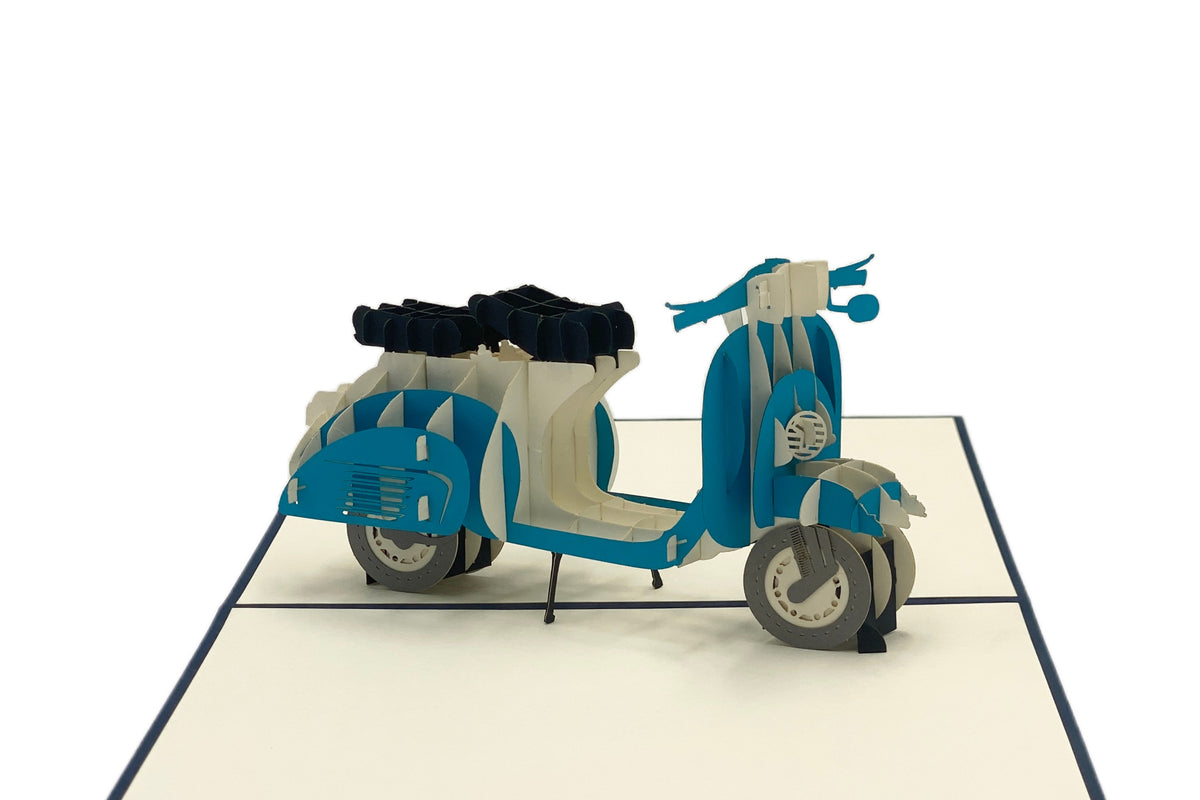 Nahaufnahme der aufgeklappten Pop-up-Karte mit einer blauen Vespa mit Gepäckträger.