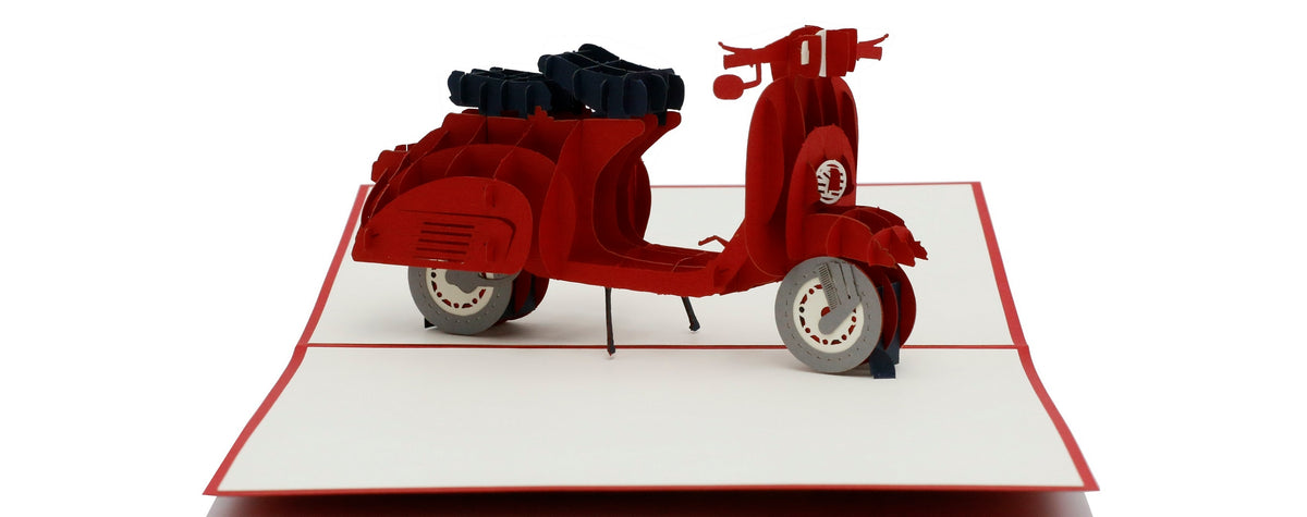 Aufgeklappte Pop-up-Karte mit einer roten Vespa aus Papier, seitlich fotografiert.