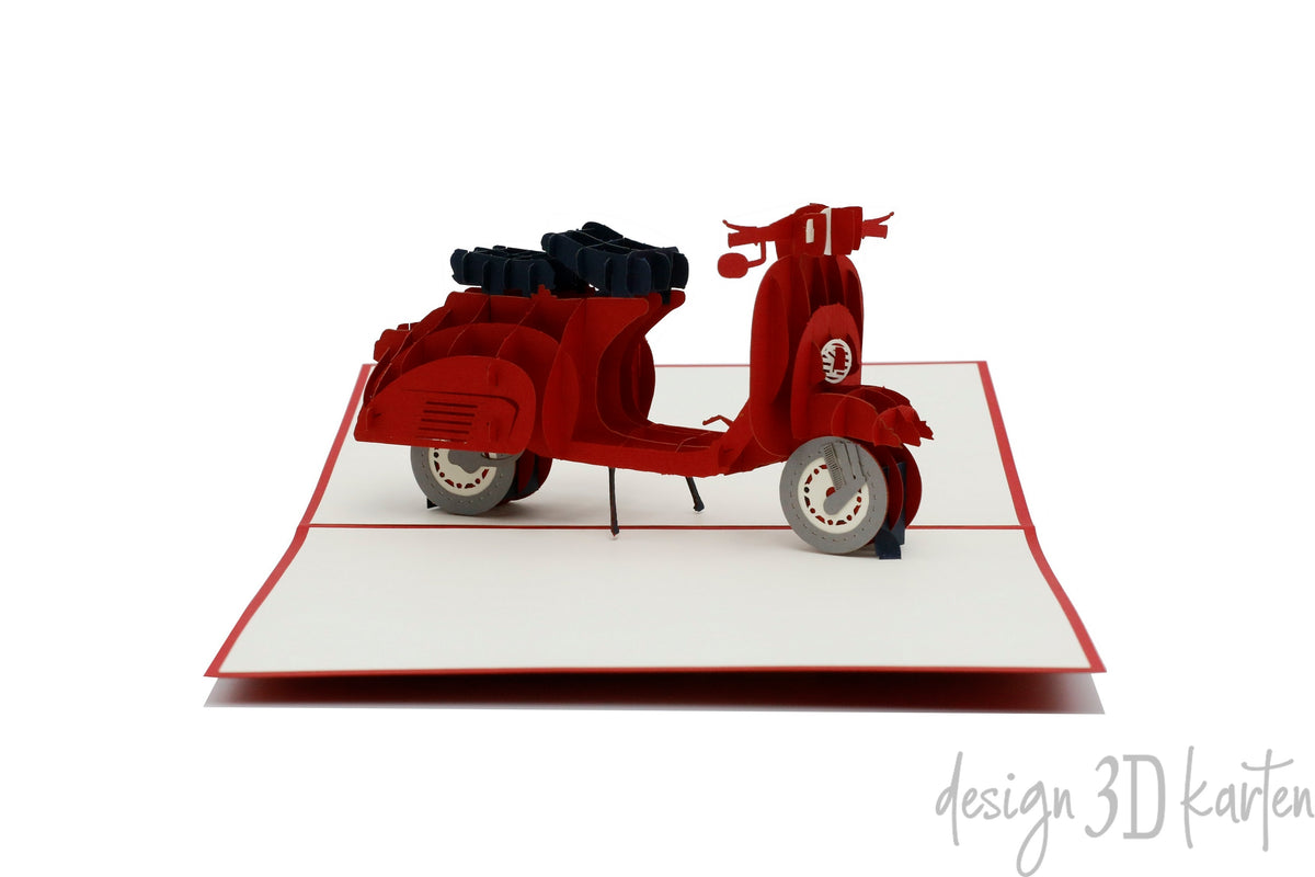Aufgeklappte Pop-up-Karte mit einer roten Vespa aus Papier, seitlich fotografiert.