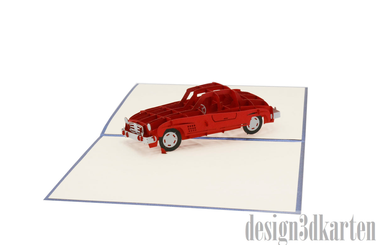 Aufgeklappte Pop-up-Karte mit blauem Rand und einem roten Oldtimer-Cabrio aus Papier.