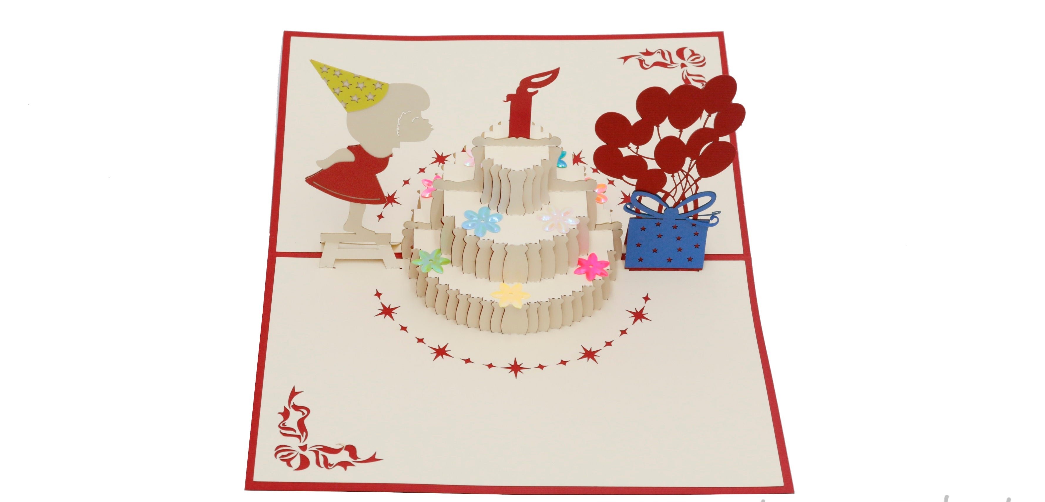 Aufgeklappte Pop-up-Karte mit rotem Rand: Geburtstagstorte mit Kerze, ein Mädchen mit Partyhut, rote Luftballons und ein blaues Geschenk.