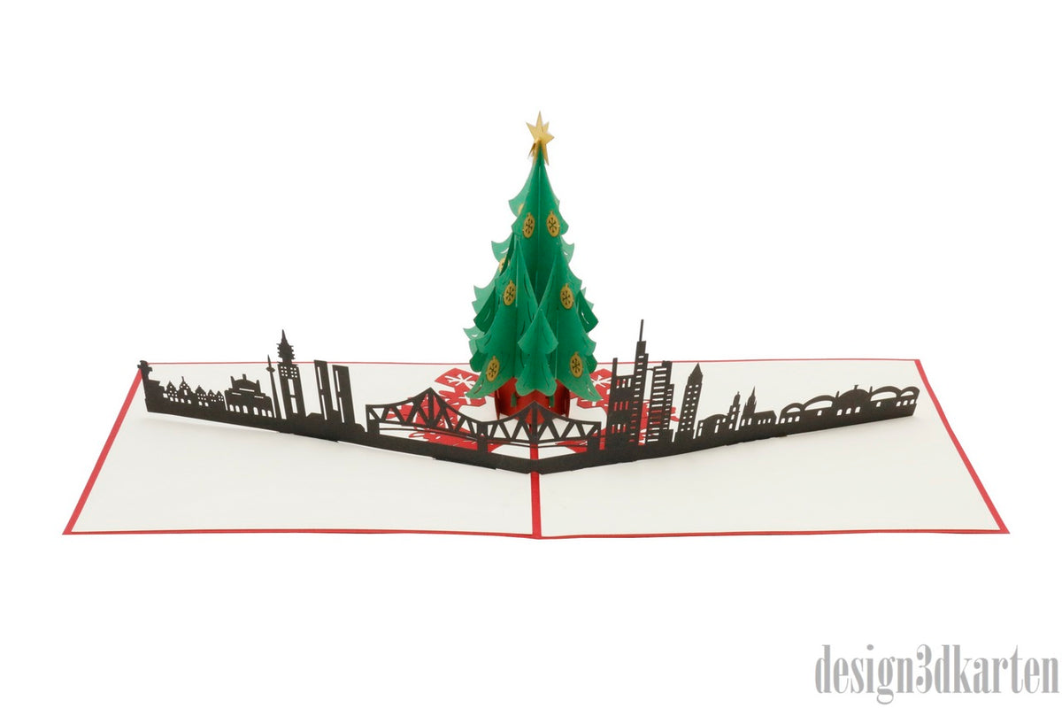 Aufgeklappte Pop-up-Karte mit Weihnachtsbaum vor der Frankfurter Skyline, schräg von der Seite fotografiert.