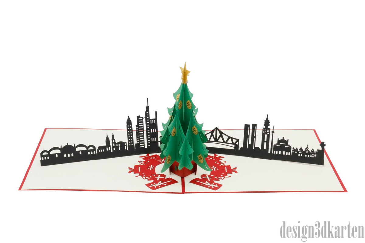Aufgeklappte Pop-up-Karte mit Weihnachtsbaum vor der Skyline von Frankfurt mit ihren Hochhäusern.