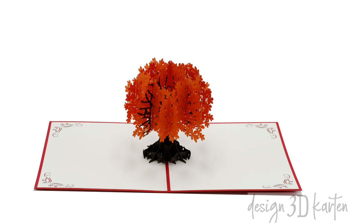 Aufgeklappte Pop-up-Karte mit einem Baum mit orangefarbenen Blättern, frontal fotografiert.
