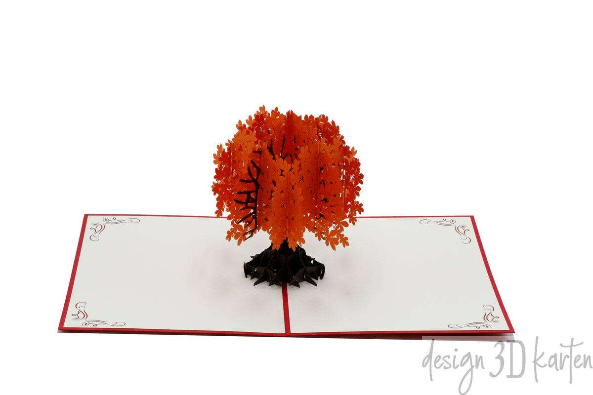 Aufgeklappte Pop-up-Karte mit einem Baum mit orangefarbenen Blättern, frontal fotografiert.