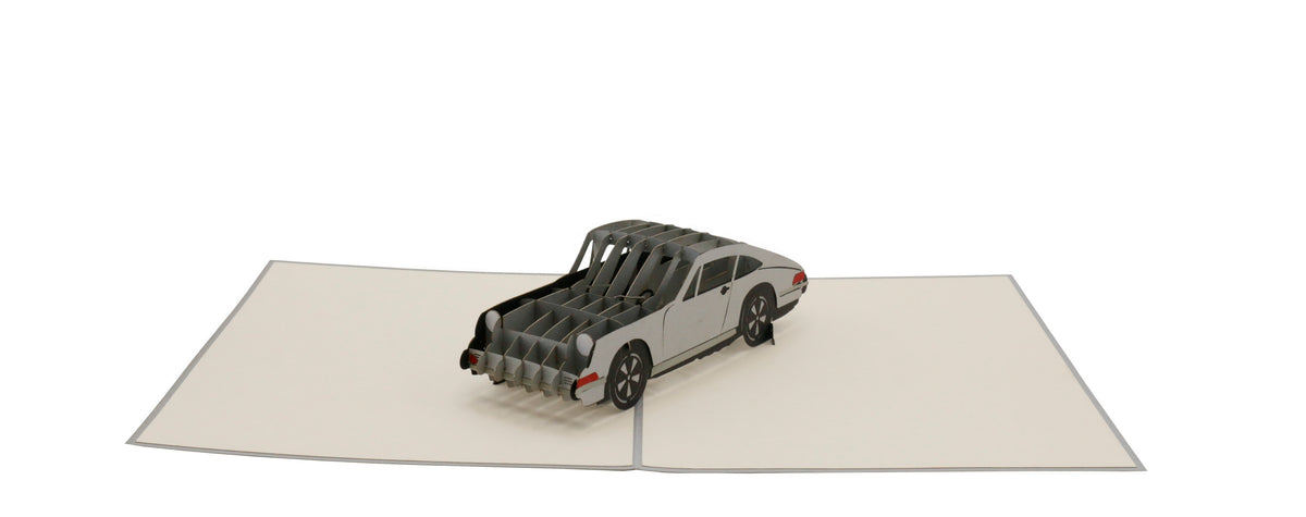 Aufgeklappte Pop-up-Karte mit silbernem Sportwagen, schräg von vorne fotografiert.