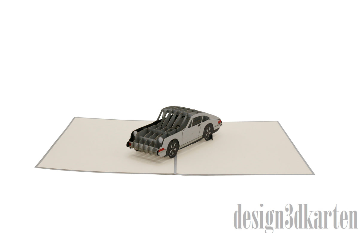 Aufgeklappte Pop-up-Karte mit silbernem Sportwagen, schräg von vorne fotografiert.
