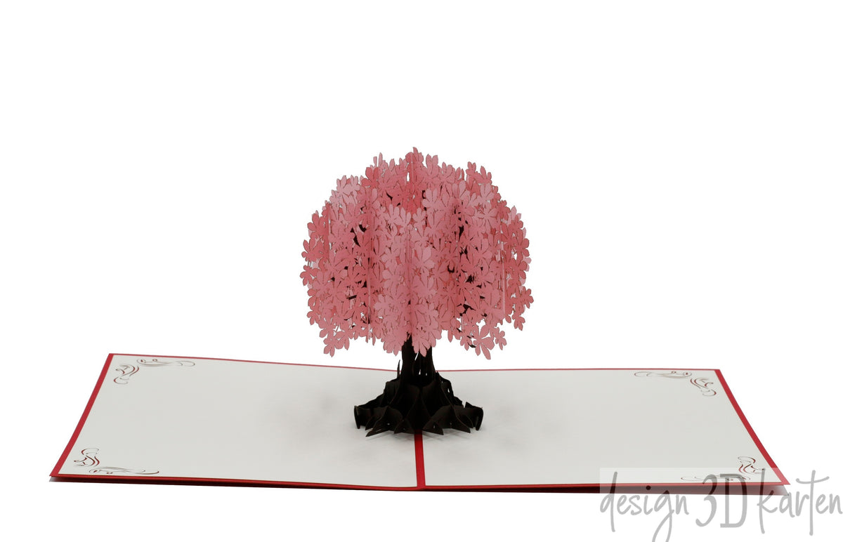 Aufgeklappte Pop-up-Karte mit einem Baum mit rosa Blüten, frontal fotografiert.