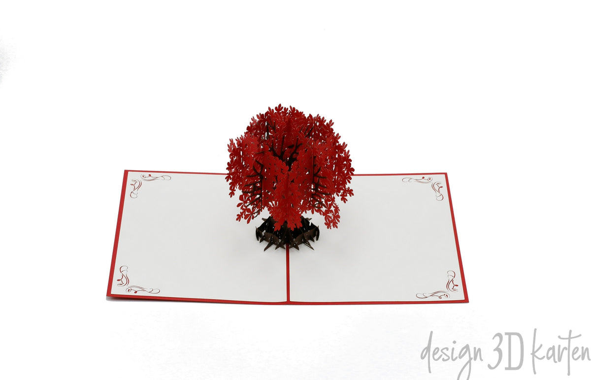 Aufgeklappte Pop-up-Karte mit rotem Blütenbaum aus Papier, frontal fotografiert.
