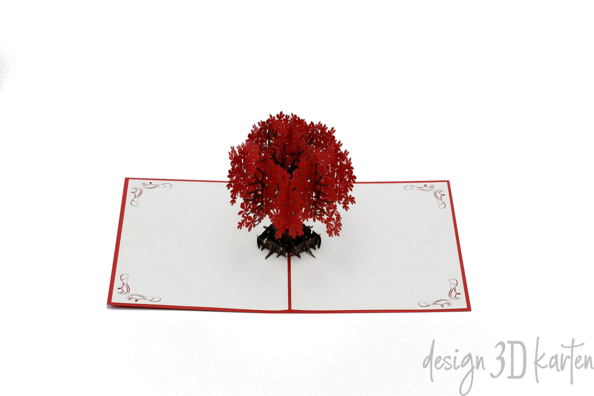 Aufgeklappte Pop-up-Karte mit rotem Blütenbaum aus Papier, frontal fotografiert.