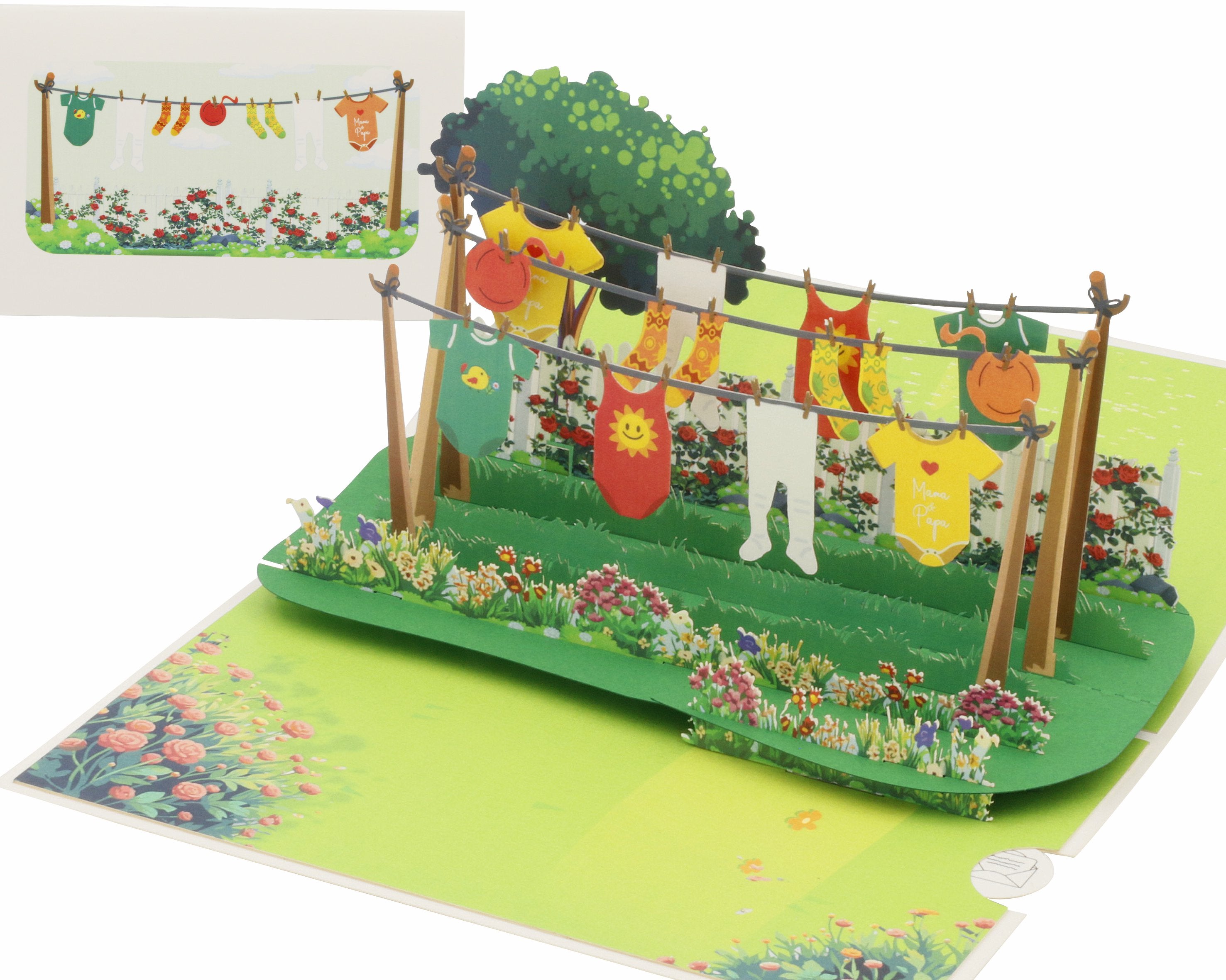 Aufgeklappte Pop-up-Karte mit Babywäsche und Stramplern auf einer Wäscheleine in einem blühenden Garten, dahinter die weiße Kartenvorderseite mit Wäscheleinen-Motiv.