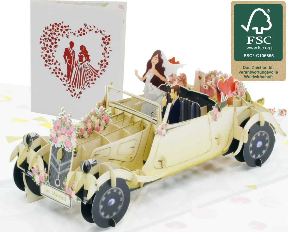 Aufgeklappte Pop-up-Karte mit einem cremefarbenen Hochzeitsauto mit Blumenschmuck und Brautpaar, daneben die Kartenvorderseite mit Herz und FSC-Logo.