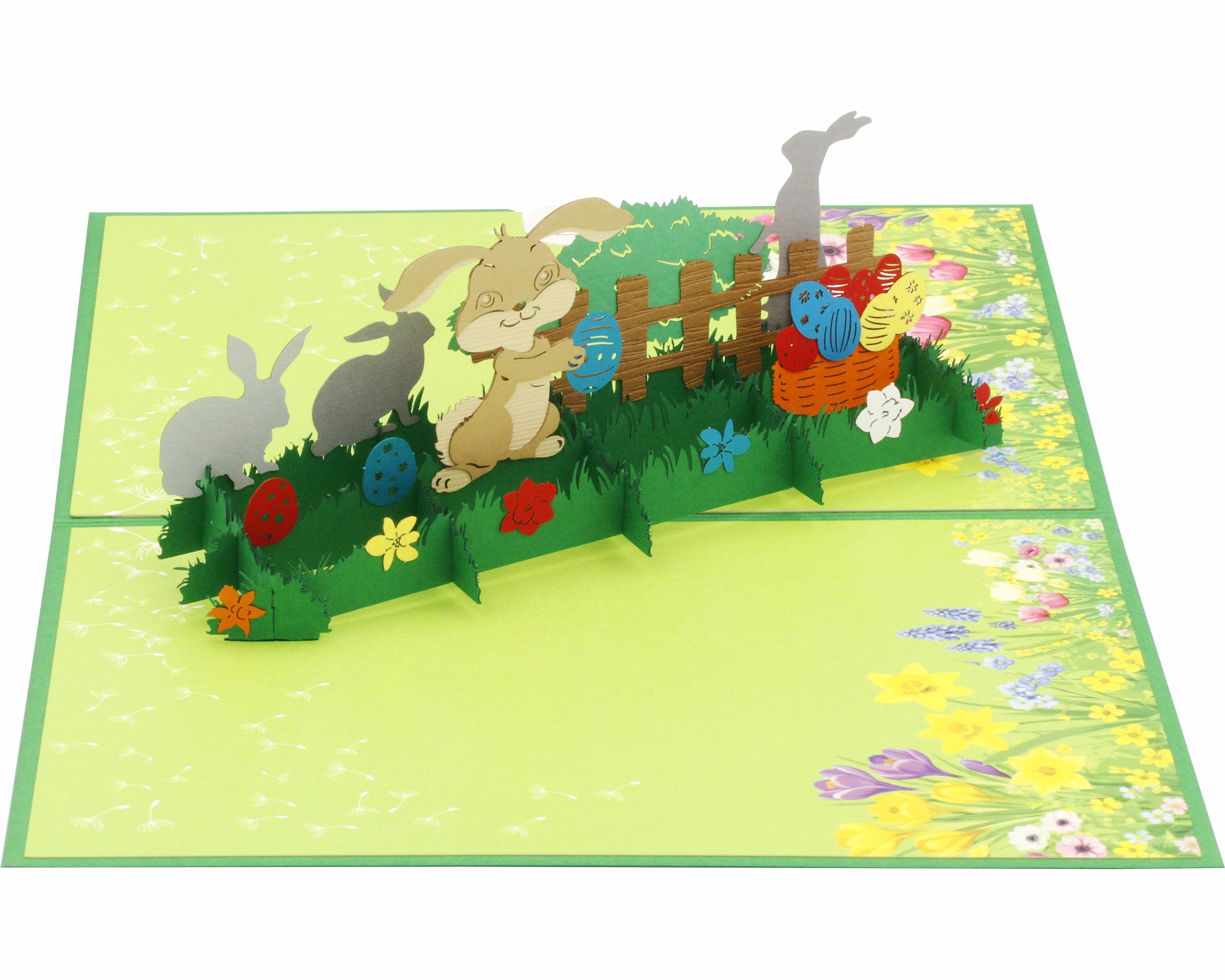 Aufgeklappte Pop-up-Karte mit Osterhasen, bunten Ostereiern und Blumen, schräg von der Seite fotografiert.