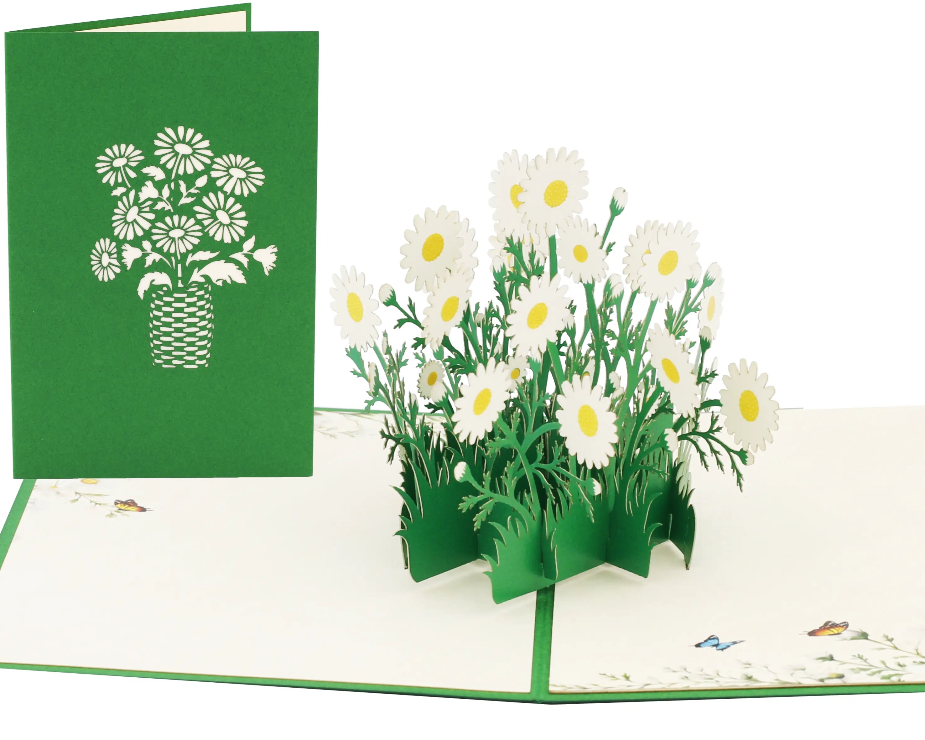 Aufgeklappte 3D Pop-up Karte mit Strauß weißer Gänseblümchen auf grüner Wiese, daneben die grüne Vorderseite mit Gänseblümchen im Korb als Scherenschnitt