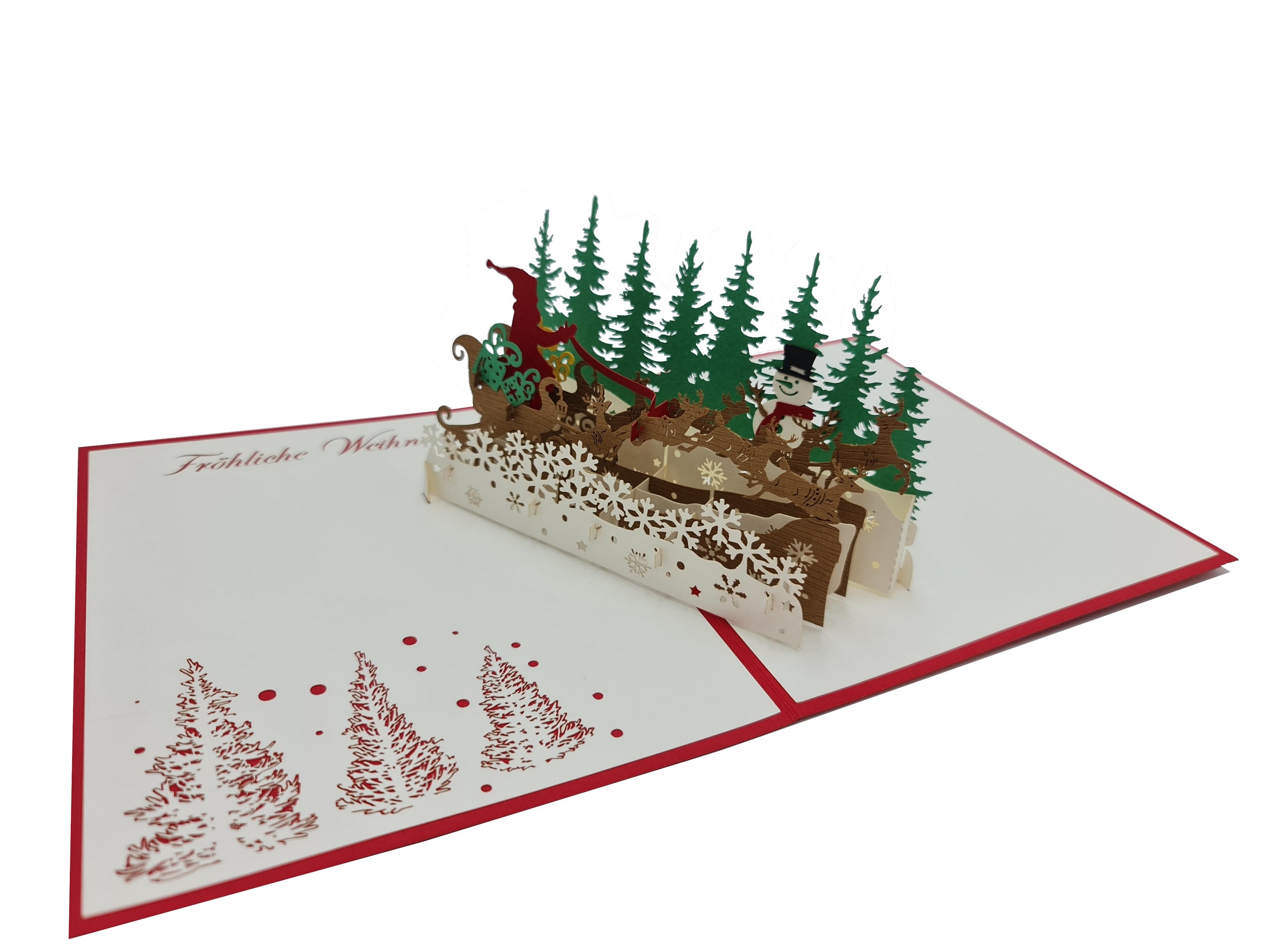 Aufgeklappte Pop-up-Karte mit fliegendem Rentierschlitten und Tannenwald aus Papier, schräg von der Seite fotografiert.